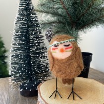 small felt owl standing on birch log pieces with christmas tree