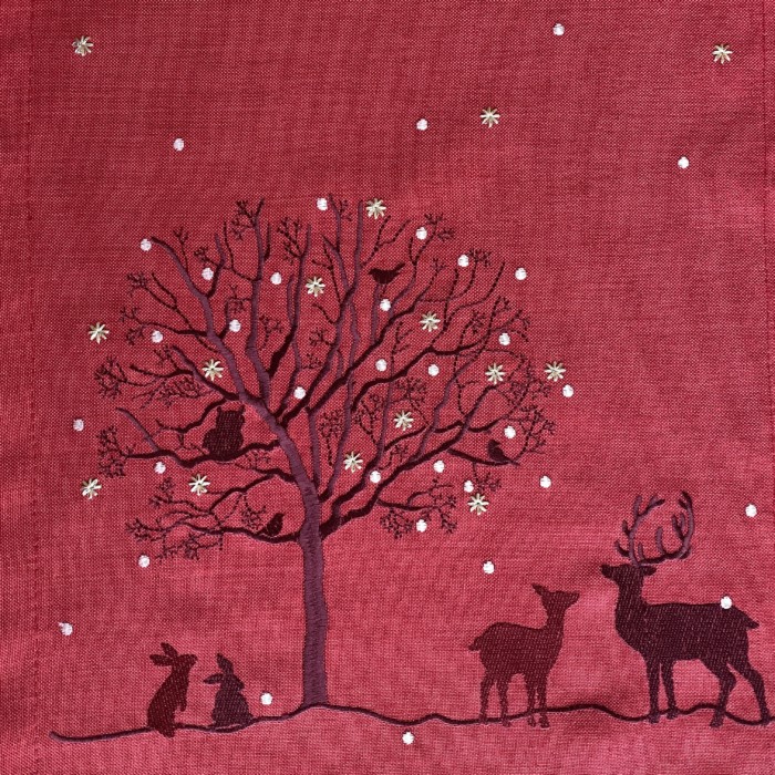 close up of dark red tblerunner embroidered with deer and a tree